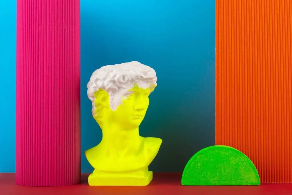 Un'esposizione artistica con il busto di una statua colorato di giallo su uno sfondo di colori azzurro, viola ed arancione